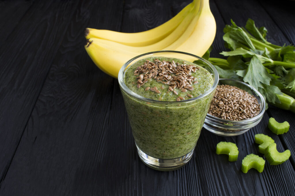 Smoothies with flax seeds, celery and banana in the glass on the black wooden background