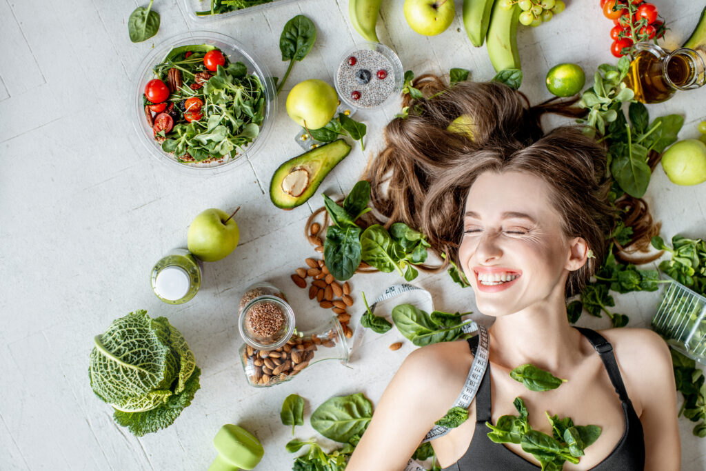 Beauty portrait of a woman surrounded by various healthy food lying on the floor. Healthy eating and sports lifestyle 